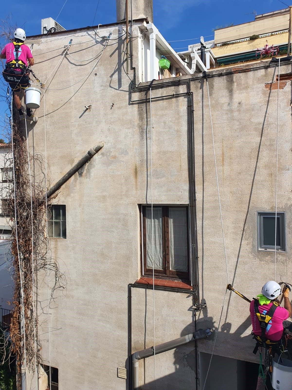 Dos técnicos de Art Vertical BCN rehabilitando un patio interior con cuerdas